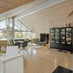 Large living and dining area with wooden ceiling and garden view.