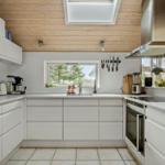 Modern kitchen with white cabinets, stainless steel stove, and skylight.
