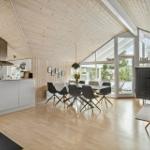 Kitchen and dining area with wooden floor and roof. Glass door leads to the terrace.