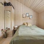 Bedroom with wooden walls, bed, window, and mirror.