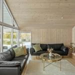 Living room with two black sofas, glass table, and wooden wall.