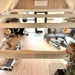 Wohnraum mit Sofa, Tisch und Stühlen unter Holzdecke