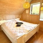 Schlafzimmer mit Holzwand, weißem Bett und Fenster mit Pflanzen.