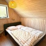 Schlafzimmer mit Holzwand, Bett und Fenster mit Vogeldekoration.