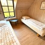 Zwei Betten in einem Holzraum mit Fenster und Tisch.