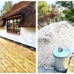 Haus mit Strohdach und Holzterrasse. Sandbeet mit Pflanzen und Metalltonne.