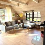 Wohnraum mit Sofa, Tisch und Fenstern. Holzdecke und -wände.