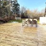 Holzterrasse mit Gartenmöbeln und Blick auf Wald.