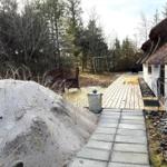 Haus mit Strohdach, Holzterrasse und Sandhügel im Wald