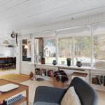 Living room with large window, sofa, and dining table in background.