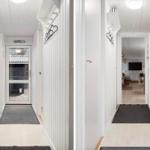 Entrance area with white walls and flooring. Door and hallway are visible.