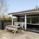 House with terrace, white table and chairs, wooden bench and black fence.