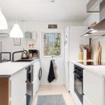 Kitchen with white cabinets, countertop, and window to the forest.