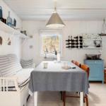 Dining room with table, chairs, and blue cabinet. Windows overlook the forest.