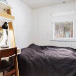 Bedroom with bed, desk, and window to the forest.