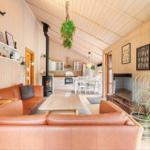 Wohnbereich mit Holzwand, Sofa, Kamin und Küchenbereich