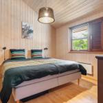 Schlafzimmer mit Holzwand, Bett und Fenster