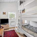 Kinderzimmer mit Doppelstockbett, Fernseher und Fenster.