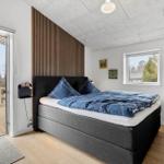 Schlafzimmer mit Bett, Fenster und Balkontür. Holzdecke und Wandverkleidung.