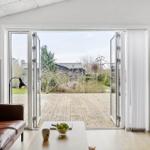 Wohnzimmer mit braunem Ledersofa und Blick auf Holzterrasse.