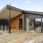 Moderne Villa mit Holzterrasse und Glasfronten. Terrasse mit Tisch und Sitzgelegenheit.