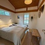 Schlafzimmer mit Doppelbett, Holzdecke und Fenster zur Terrasse.