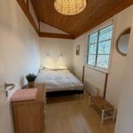 Schlafzimmer mit Bett, Schrank, Fenster und Deckenleuchte.