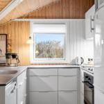 Kitchen with wooden wall, window, and white cabinets.