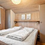 Bedroom with wooden walls, bed, and window. Wall art and ceiling light.