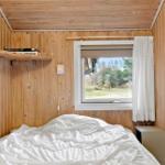 Bedroom with wooden walls, bed, and window overlooking green areas.