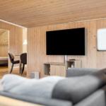 Living room with TV and wooden walls. Dining area visible in the background.