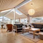 Living and dining area with wooden ceiling, sofa, table, and windows.