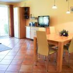 Essbereich mit Holztisch und Stühlen, Fernseher und Schlafzimmer mit Sofa.