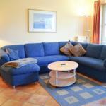 Ein Wohnzimmer mit blauem Sofa, runden Tisch und Teppich.