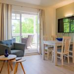 Wohn- und Essbereich mit Balkon, TV und Holzmöbel.