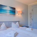 Schlafzimmer mit Doppelbett, Wandbild und Kleiderschrank.