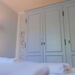 Schlafzimmer mit Bett, Kleiderschrank und Wandlampe.