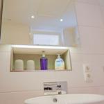 Badezimmer mit Spiegel, Waschbecken und Aufbewahrungsfach