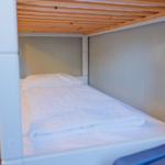 Unterbett mit weißer Bettwäsche und Holzdecke