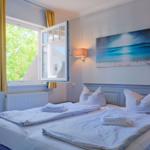 Ein Schlafzimmer mit Bett, Fenster und Wandbild.