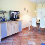 Wohn- und Essbereich mit TV, Tisch und Stühlen sowie Küche im Hintergrund.