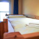 Schlafzimmer mit Holzbett, weißen Bettwäsche und Fenster mit blauen Vorhängen.