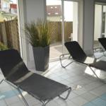 Terrasse mit Liegestühlen und Pflanzen. Durchgang zu Garten und Wohnbereich.