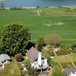 Haus mit Terrasse, umgeben von Grünflächen und einem See.