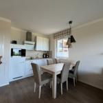 Küche mit Esstisch, Fenster und Wohnbereich mit Sofa.