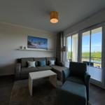 Wohnzimmer mit Sofa, Sessel und Balkonblick