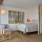 Schlafzimmer mit Bett, Sofa, Holztisch und Wandbild von Birken.