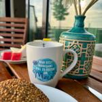 Frühstück auf Terrasse mit Kaffeetasse, Brot und Blumen