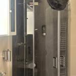 Duschkabine mit Glaswand, Handtuchhalter und Duschbrause.