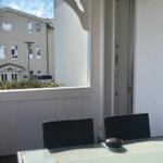 Terrasse mit Tisch und Stühlen, Blick auf Nachbarhaus und Garten.